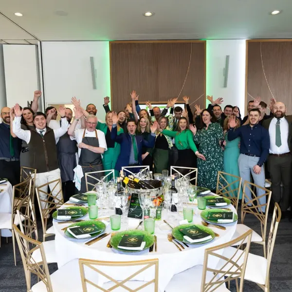 Team photograph with everyone waving, showing Green & Fortune family atmosphere
